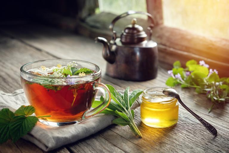 A cup of tea with fresh herbs and honey