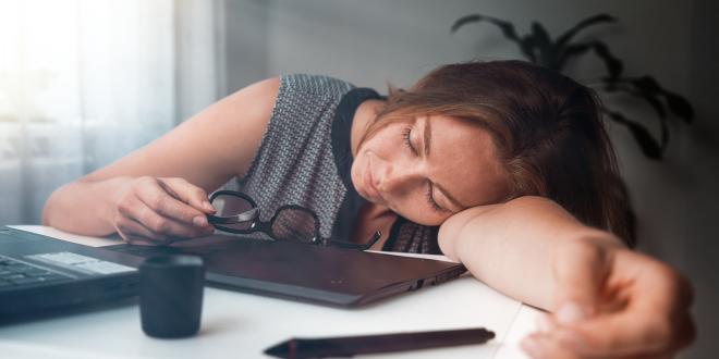 A young woman that has fallen asleep while working on her computer.