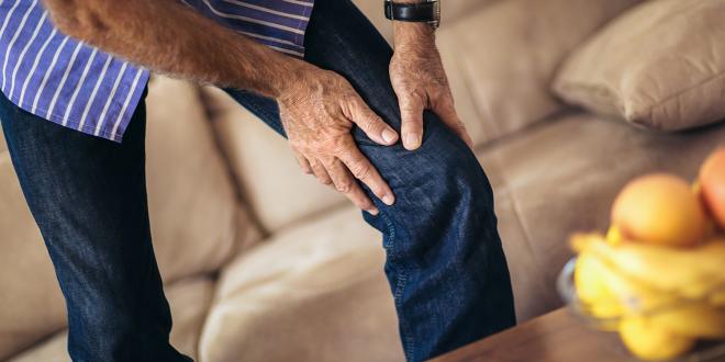 a middle-aged man grabbing his bad knee in pain