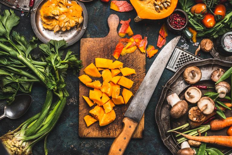 a kitchen knife on a cutting board of sliced and diced fruits and vegetables